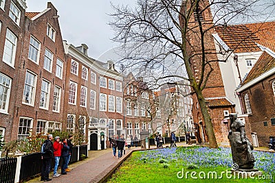 Begijnhof courtyard with tourists, statue and historic houses in Amsterdam, Netherlands Editorial Stock Photo