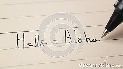 Beginner Hawaiian language learner writing Hello word Aloha for homework on a notebook Stock Photo
