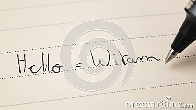 Beginner Polish language learner writing Hello word Witam for homework on a notebook Stock Photo