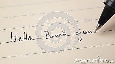 Beginner Romanian language learner writing Hello word Buna ziua for homework on a notebook Stock Photo