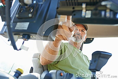 The beginning of the farming day. Shot of a farmer working inside the cab of a modern tractor. Stock Photo