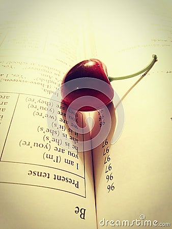 The beginning of the school year. English language training. Open textbook, dictionary-translator and cherry-shaped bookmark. Stock Photo