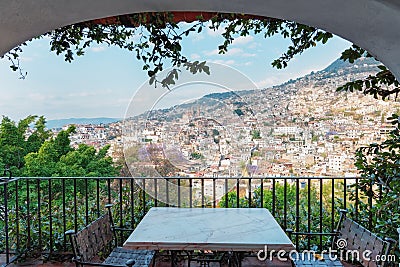 Behind the balcony of the hotel is a city on the slopes of the mountains. Stock Photo