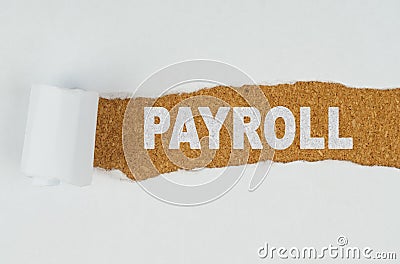 Behind torn white paper on a wooden background the text - PAYROLL Stock Photo