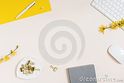 On a beige background flat lay with a yellow flower, a notepad keyboard and paper clips, a female floral desktop. Stock Photo