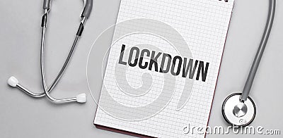 On a beige background, a stethoscope and a white notepad with the inscription LOCKDOWN. Medical concept Stock Photo