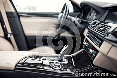 Beige and black interior of modern car, close-up details of automatic transmission and gear stick against steering wheel ba Stock Photo