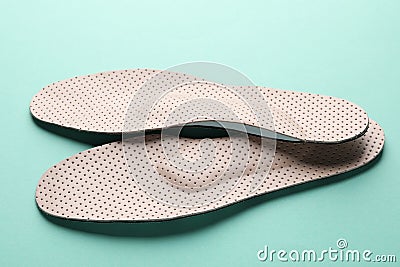 Beige comfortable orthopedic insoles on turquoise background, closeup Stock Photo