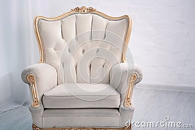 Beige leather wood armchair with golden decor in a white living room Stock Photo