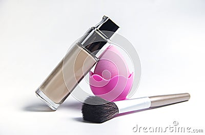 A makeup sponge. Makeup brush and makeup base. Beige liquid foundation for makeup, applied with a brush, isolated on Stock Photo