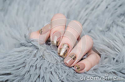 beige Nude manicure with gold lace pattern on a gray background Stock Photo