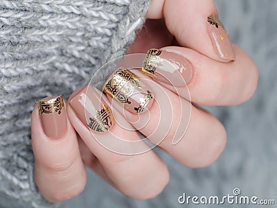 beige Nude manicure with gold lace pattern on a gray background Stock Photo