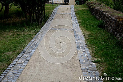 Beige threshing path gravel with delimited edges granite cubes in a row and dividing channels from the cube trough channel due Stock Photo