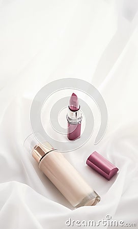 Beige tonal cream bottle make-up fluid foundation base and pink lipstick on silk background, cosmetics products as luxury beauty Stock Photo