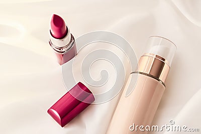 Beige tonal cream bottle make-up fluid foundation base and red lipstick on silk background, cosmetics products as luxury beauty Stock Photo