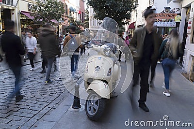 A beige Vespa Scooter at streets of Beyoglu, Istanbul and blurry people Editorial Stock Photo