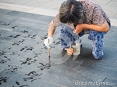 Older woman practicing water calligraphy Editorial Stock Photo