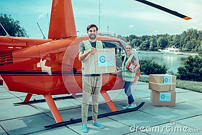 Positive cheerful guys being experienced volunteers and collecting boxes with help Stock Photo