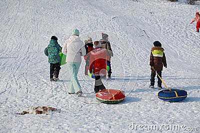 Parents and children ride from the snow slides in winter have fun resting in nature. Editorial Stock Photo