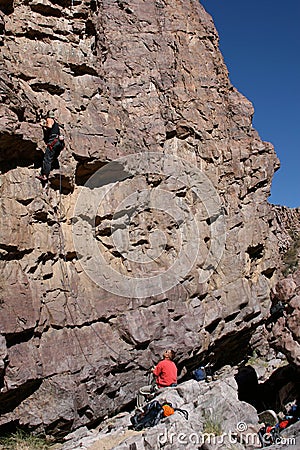 Belayer below climber on wall Stock Photo