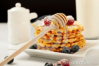 Belgian waffles with raspberries and sieving sugar powder and honey served with jug of milk on a white table Stock Photo