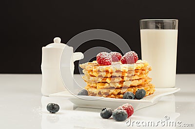 Belgian waffles with raspberries and sieving sugar powder and honey served with jug of milk on a white table Stock Photo