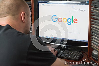 Belgorod, Russia - December 11, 2017: Man uses Google search. A white man sitting at the computer. On the monitor before his eyes Editorial Stock Photo