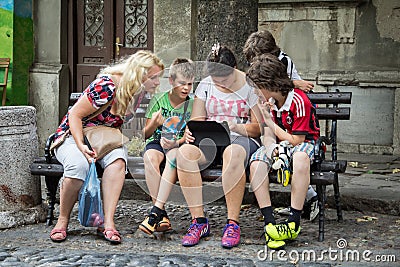 White Caucasian family, a mother and her daughters and sons, watching an iPad tablet outdoors, sitting and browsing the internet Editorial Stock Photo