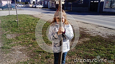 Belgrade, Serbia. February 22, 2020. A 6-year-old girl hides behind a thin tree. A child with glasses. Peekaboo Stock Photo