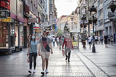 Young people, a couple, walking and holding hands in a Belgrade street wearing face mask Editorial Stock Photo