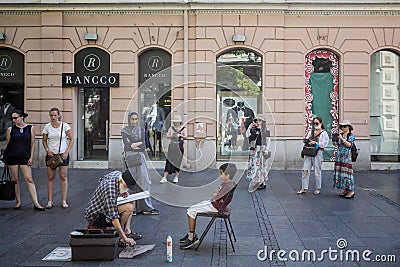 Street cartoonist drawing the caricature of a children in Kneza Mihailova, the main street of Belgrade, Serbia, Editorial Stock Photo