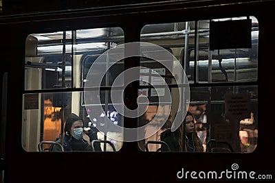 Selective blur on commuter passengers in a tram, one wearing a respiratory face mask, the other not Editorial Stock Photo