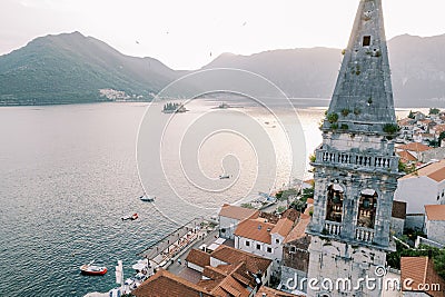 Bell tower of the Church of St. Nicholas among ancient houses against the backdrop of the islands of the Bay of Kotor Stock Photo