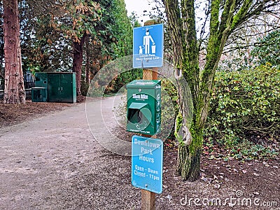 View of a doggie bag station at the downtown Bellevue Park, with the park hours posted below Editorial Stock Photo