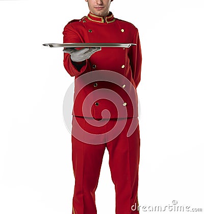 Bellhoper with red uniform presents a tray. Stock Photo