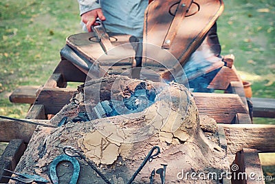 The bellows of the blacksmith and the blacksmith blowing the coals for forging. Retro forge on outdoor in summer day Stock Photo