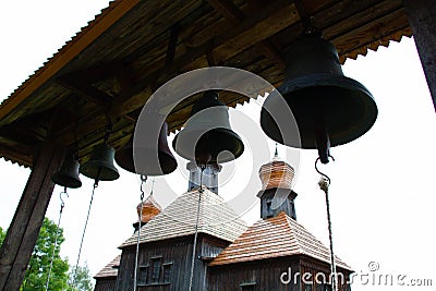 Bells near the church. Massive cast-iron prayer bells against the backdrop of a Christian Orthodox wooden church. Ancient catholic Stock Photo