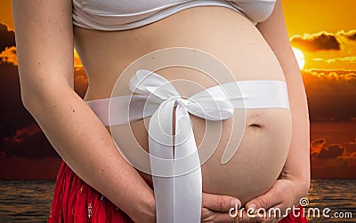 Belly of a pregnant woman with bowknot Stock Photo