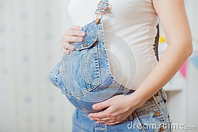 Belly of a pregnant woman in a denim overalls Stock Photo