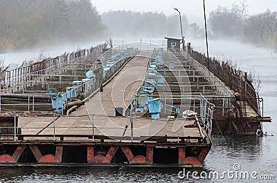 Beloozersk, Belarus, November 11, 2018: fish industry. man feeds and breeds fish. Autumn cold day. The fog spreads over the water Editorial Stock Photo