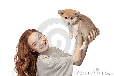 Cheerful redhead young girl with long curly hair holding cute little puppy of corgi dog isolated on white background Stock Photo