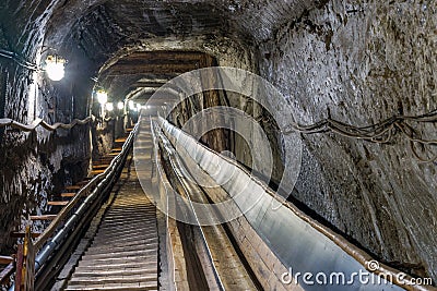 Belt conveyot in illuminated underground tunnel Stock Photo