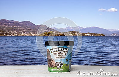 Ben Jerry`s Chocolate Fudge Brownie Ice Cream on white wooden table against blue water and mountains background Editorial Stock Photo