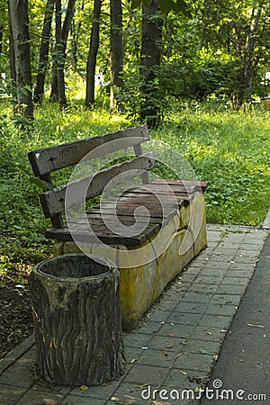 Bench, garbage container, asphalt path in the park Stock Photo