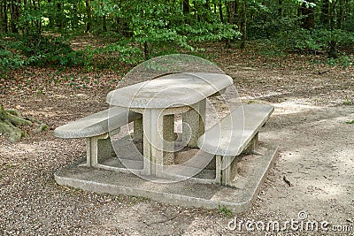 A bench made of concrete and ceramics outside in a luscious green forest during summer or spring. A quiet place to enjoy Stock Photo