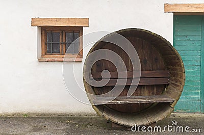 Bench in an old wine barrel in front of an old house Stock Photo