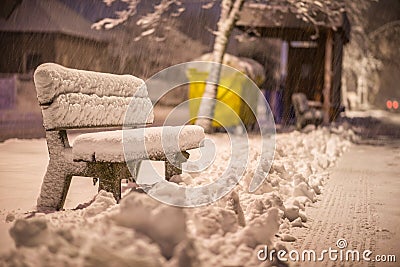 Bench with snow after snowstorm or in snow calamity in europe, winter night photograhy in city Stock Photo