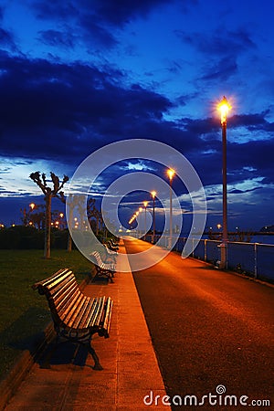 Benches and lampposts in a park at night Stock Photo