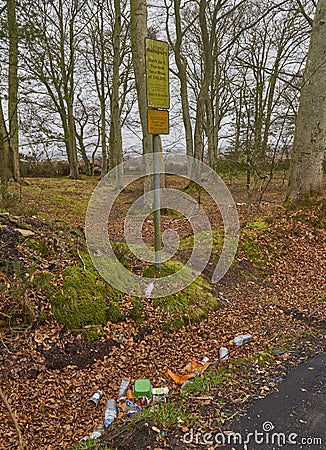 Beneath a sign stating that people will be fined for Fly Tipping Rubbish, lies all sorts of garbage. Editorial Stock Photo