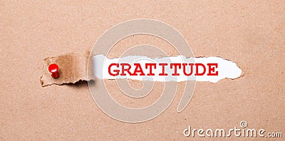 Beneath the torn strip of kraft paper attached with a red button is a white paper GRATITUDE Stock Photo